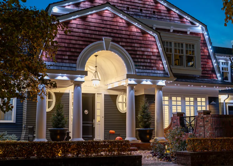 Shingled home with lit columns and a rounded portico