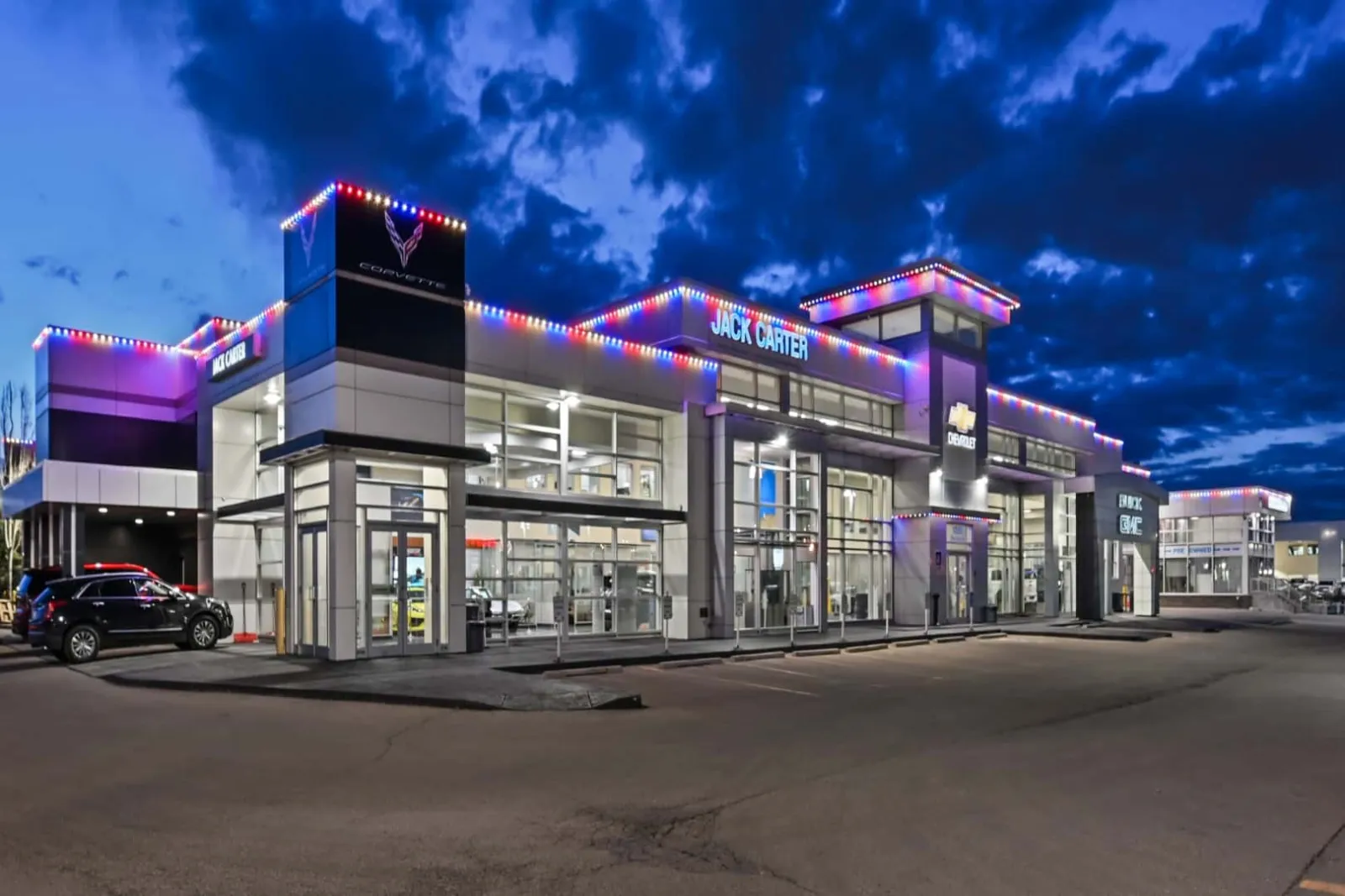 Retail plaza at dusk with colored lights along its rooflines