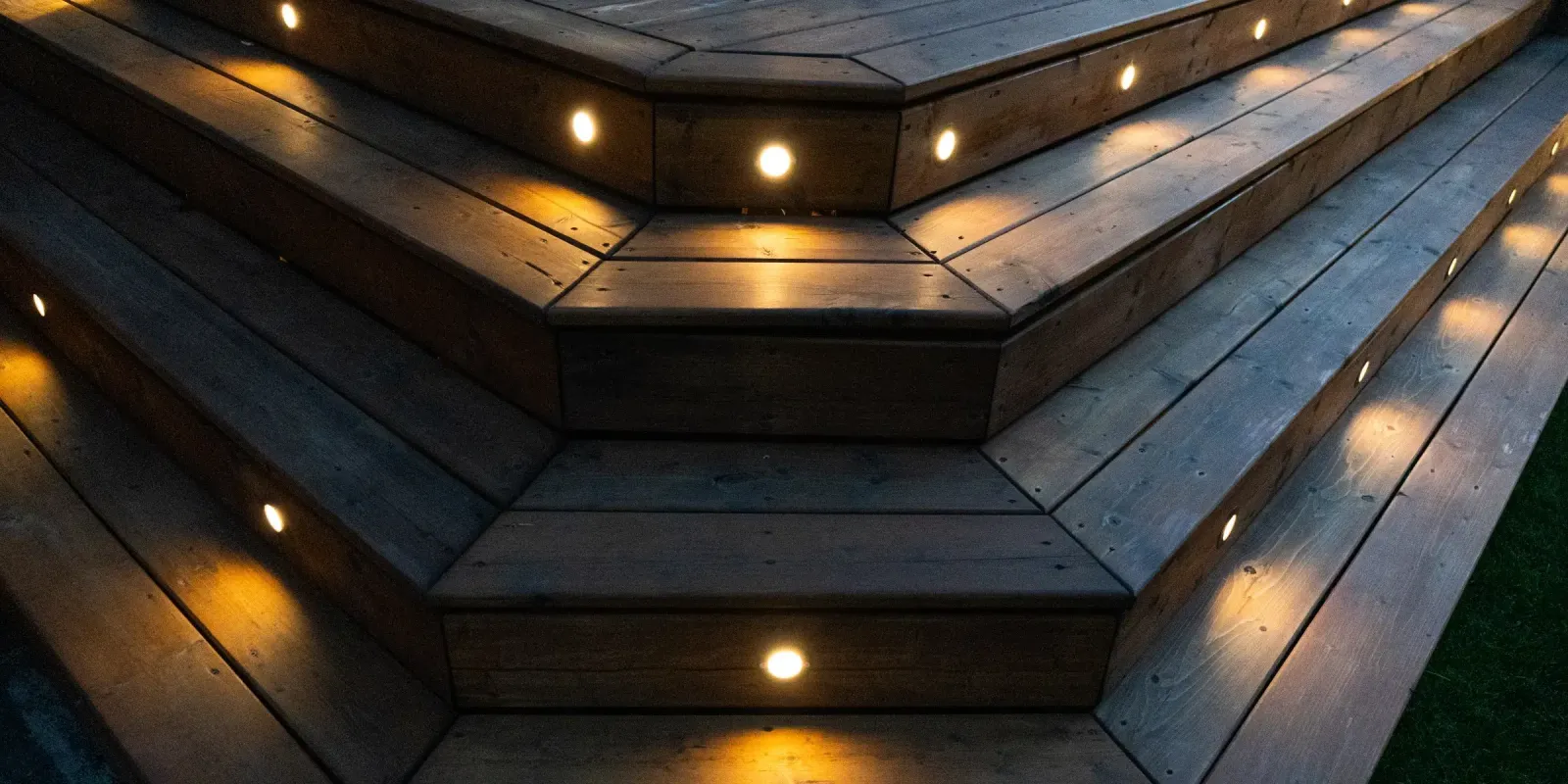Wide wooden deck steps at night with small warm white lights set into each tread