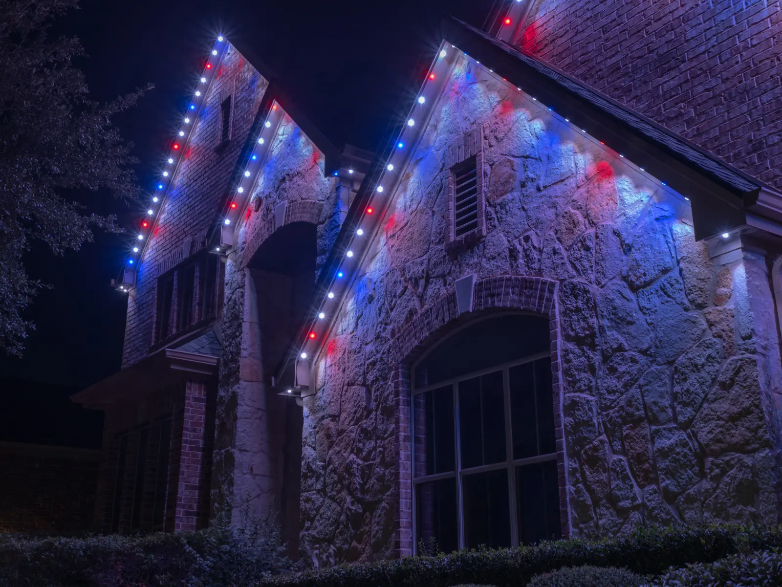 Stone and brick gables at night outlined in alternating red, white and blue lights