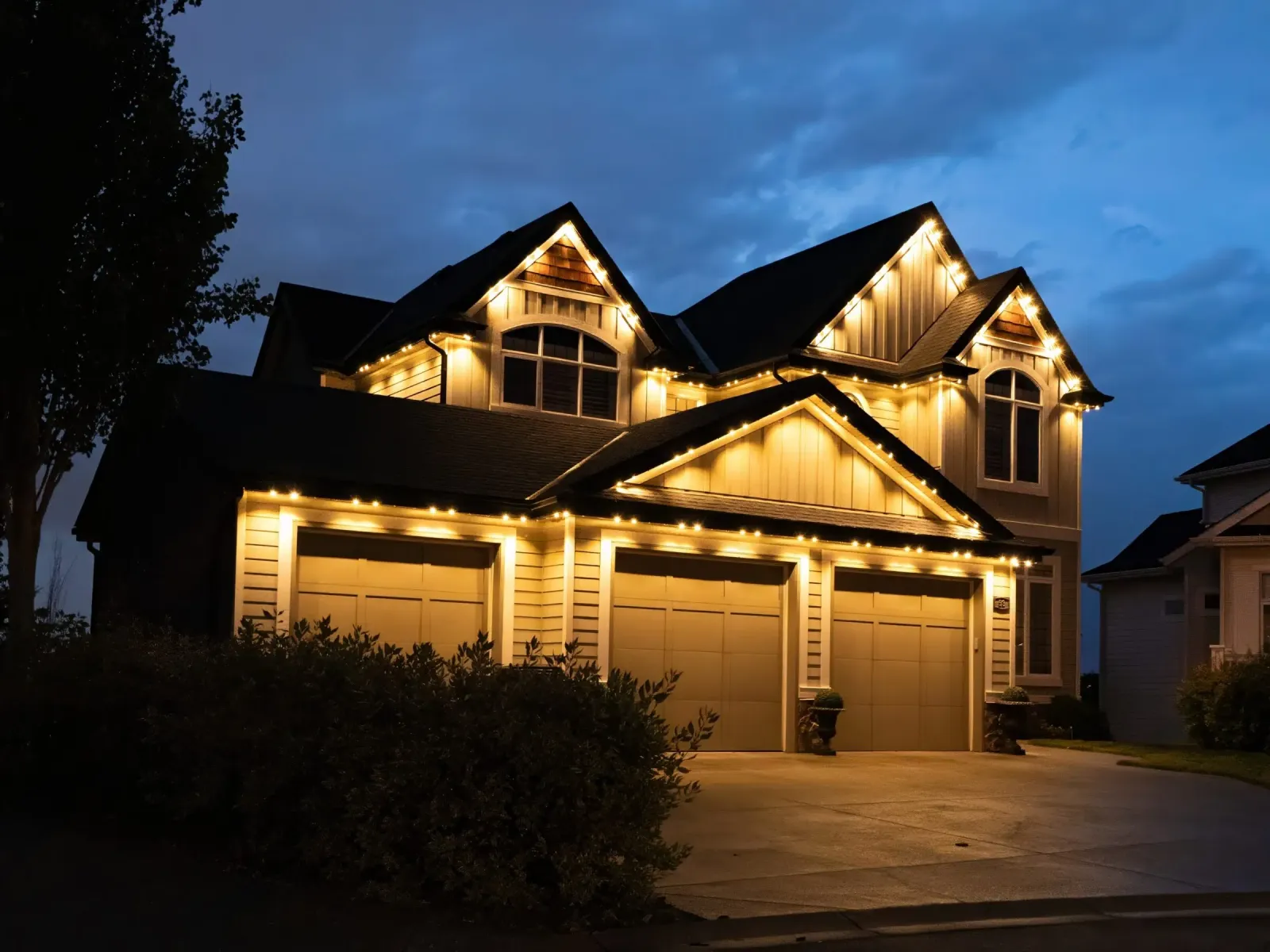 The same house at dusk with warm white lights along every roofline